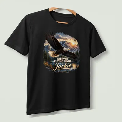 Realistic Bald Eagle soaring with text 'FOREVER FLYING HIGH Jackie 2012 - 2026' — printed on a unisex t-shirt (angled view)