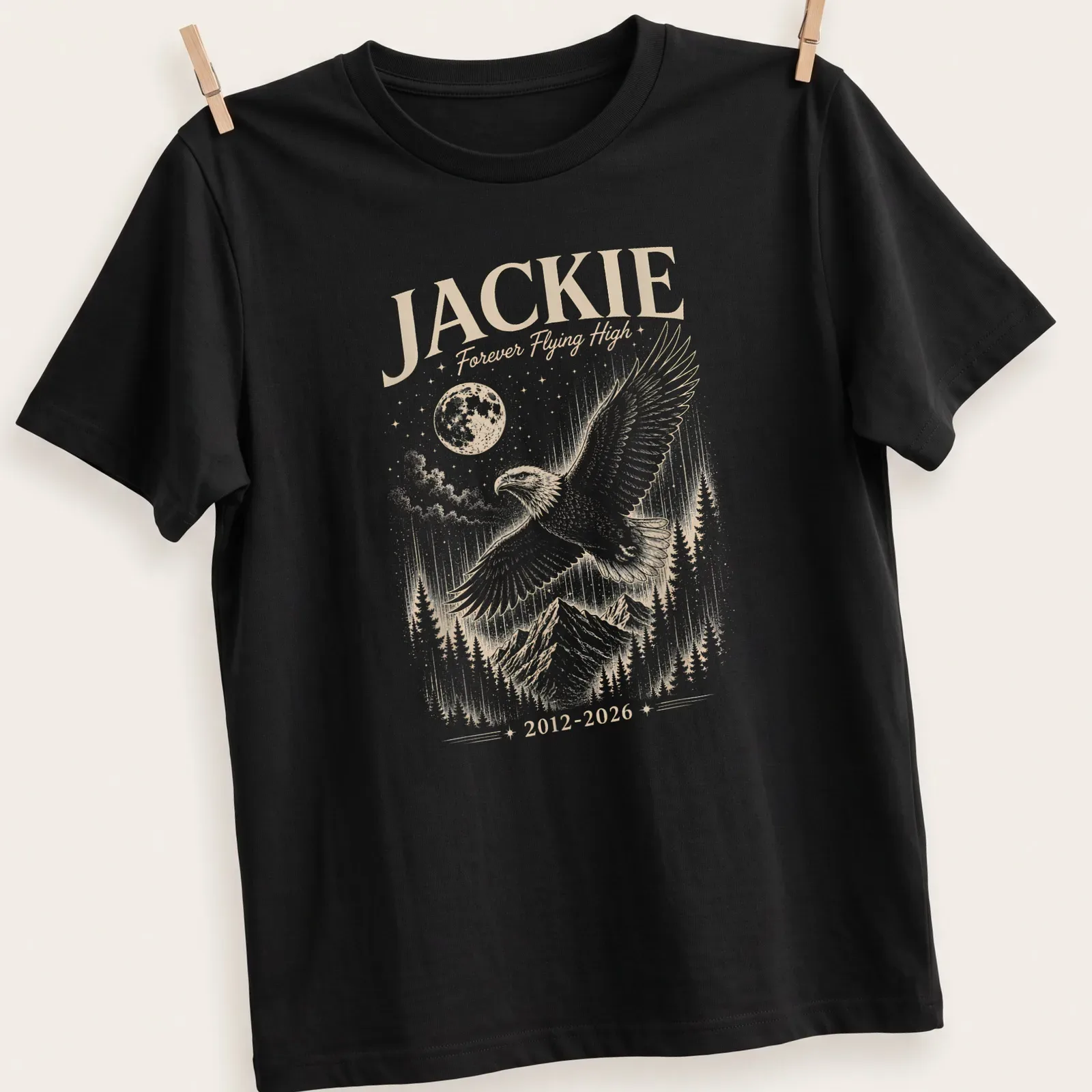 Detailed illustration of a bald eagle with the text Jackie Forever Flying High 2012 2026 — printed on a unisex t-shirt
