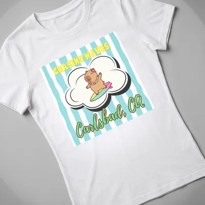 Cute cartoon capybara surfing with cheerful colors and text — printed on a women's shirt