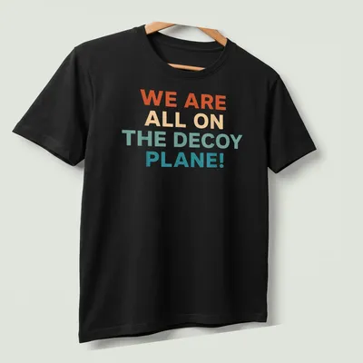 Colorful decoy plane graphic with bold text proclaiming we are all on the decoy plane — printed on a unisex t-shirt (angled view)