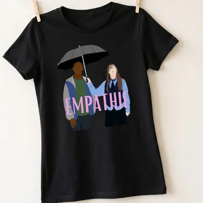 Flat design of two figures sharing an umbrella with the word 'EMPATHIE' above them — printed on a women's shirt