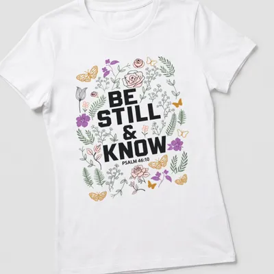 Floral design with the text 'BE STILL & KNOW PSALM 46:10' in vibrant colors — printed on a women's shirt
