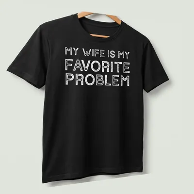 Bold typography T-shirt with the text 'MY WIFE IS MY FAVORITE PROBLEM' in white — printed on a unisex t-shirt (angled view)