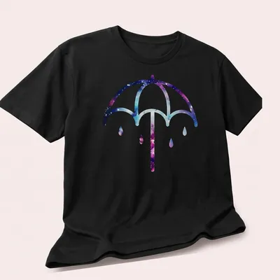 Illustration of a purple umbrella on a cosmic galaxy background in purple, blue, pink, and white — printed on a unisex t-shirt (angled view)