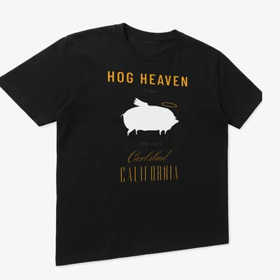 Modern typography t-shirt featuring Hog Heaven Carlsbad California text in orange and white — printed on a unisex t-shirt (angled view)
