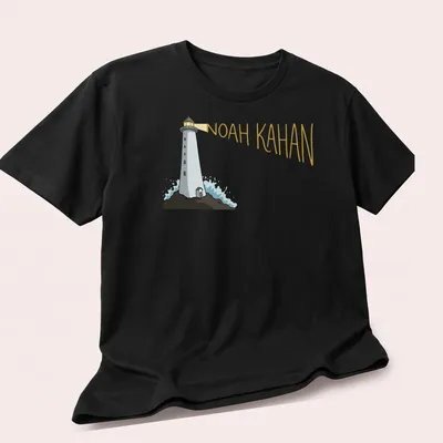 Cartoon lighthouse design with 'Noah Kahan' text in white, blue, and yellow — printed on a unisex t-shirt (angled view)