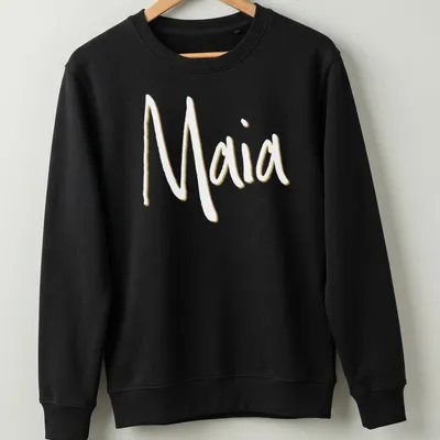 Personalized T-shirt featuring the name Maia in gold and white typography — printed on a unisex sweatshirt