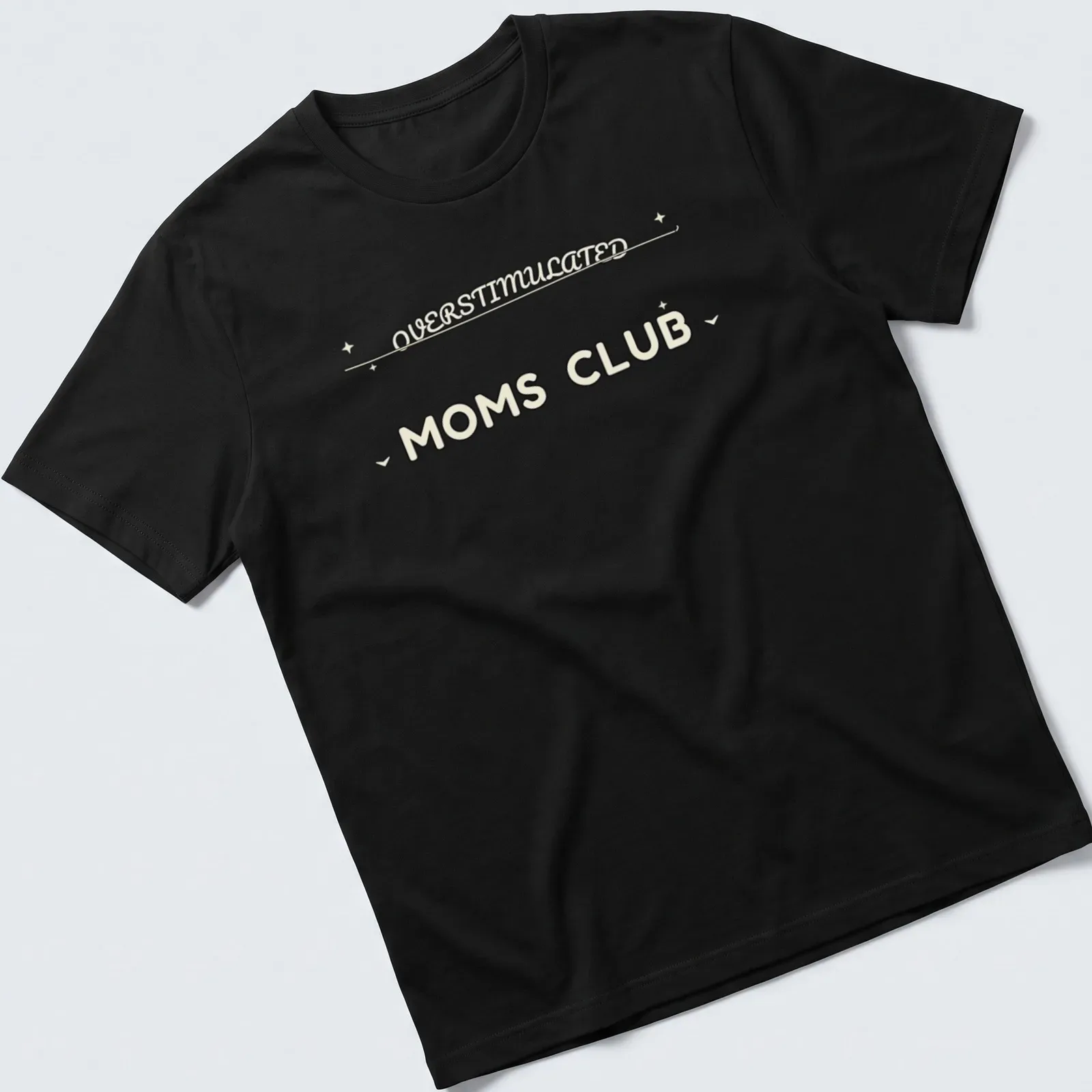 Moms Club t-shirt with 'Overstimulated Moms Club' in rounded bubble lettering on a cream background — printed on a unisex t-shirt