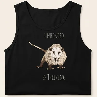 Sketch illustration of an opossum with the text 'UNHINGED & THRIVING' in earthy colors — printed on a tank top