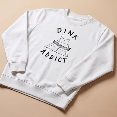 Line-art pickleball court with bold text 'DINK ADDICT' in black and white — printed on a unisex sweatshirt