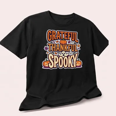 Playful cartoon graphic of pumpkins with 'GRATEFUL THANKFUL SPOOKY' text — printed on a unisex t-shirt (angled view)