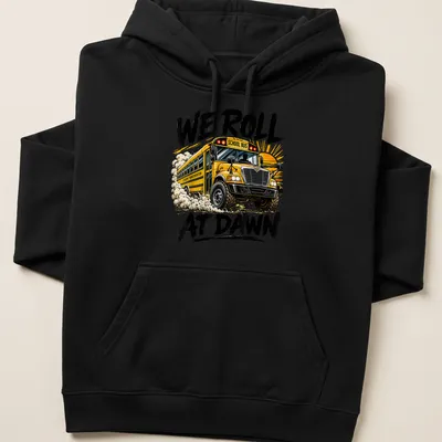 Bold graphic t-shirt featuring a school bus and the phrase We Roll At Dawn — printed on a unisex hoodie