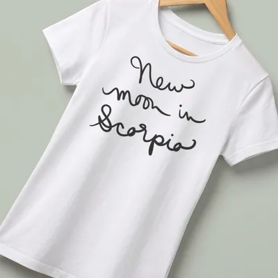 Black shirt with handwritten text 'New moon in Scorpio' in elegant script. — printed on a women's shirt