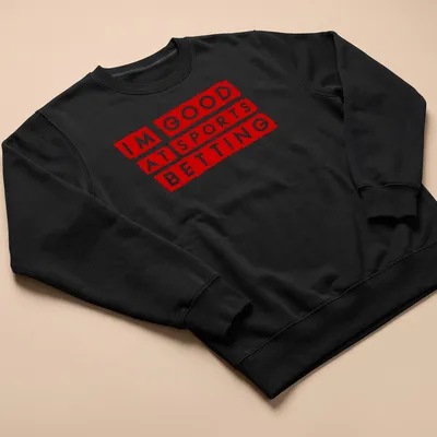 Bold graphic t-shirt featuring the phrase 'I'm Good At Sports Betting' in red and white — printed on a unisex sweatshirt